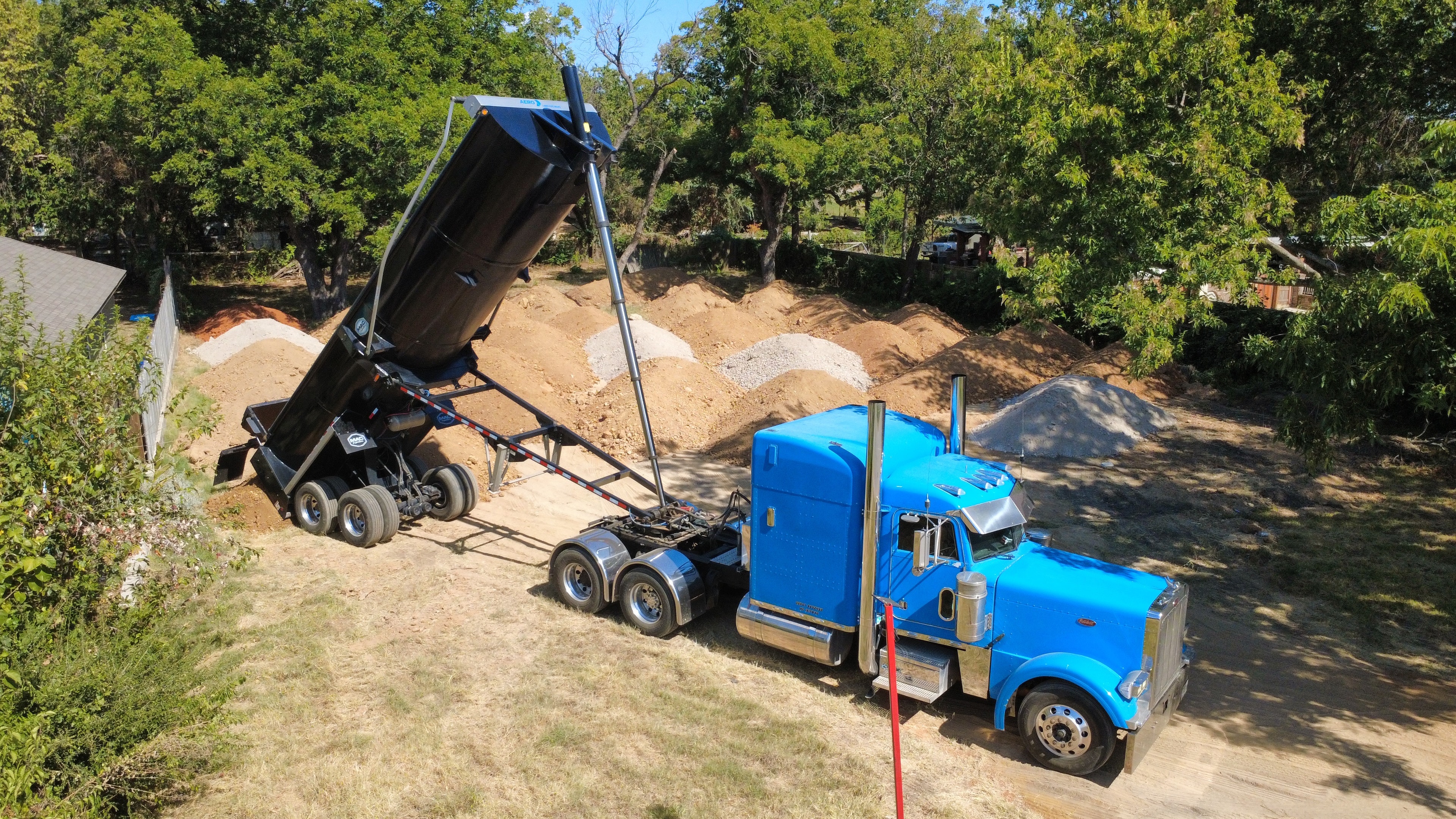 Blue dump truck unloading aggregate material on job site